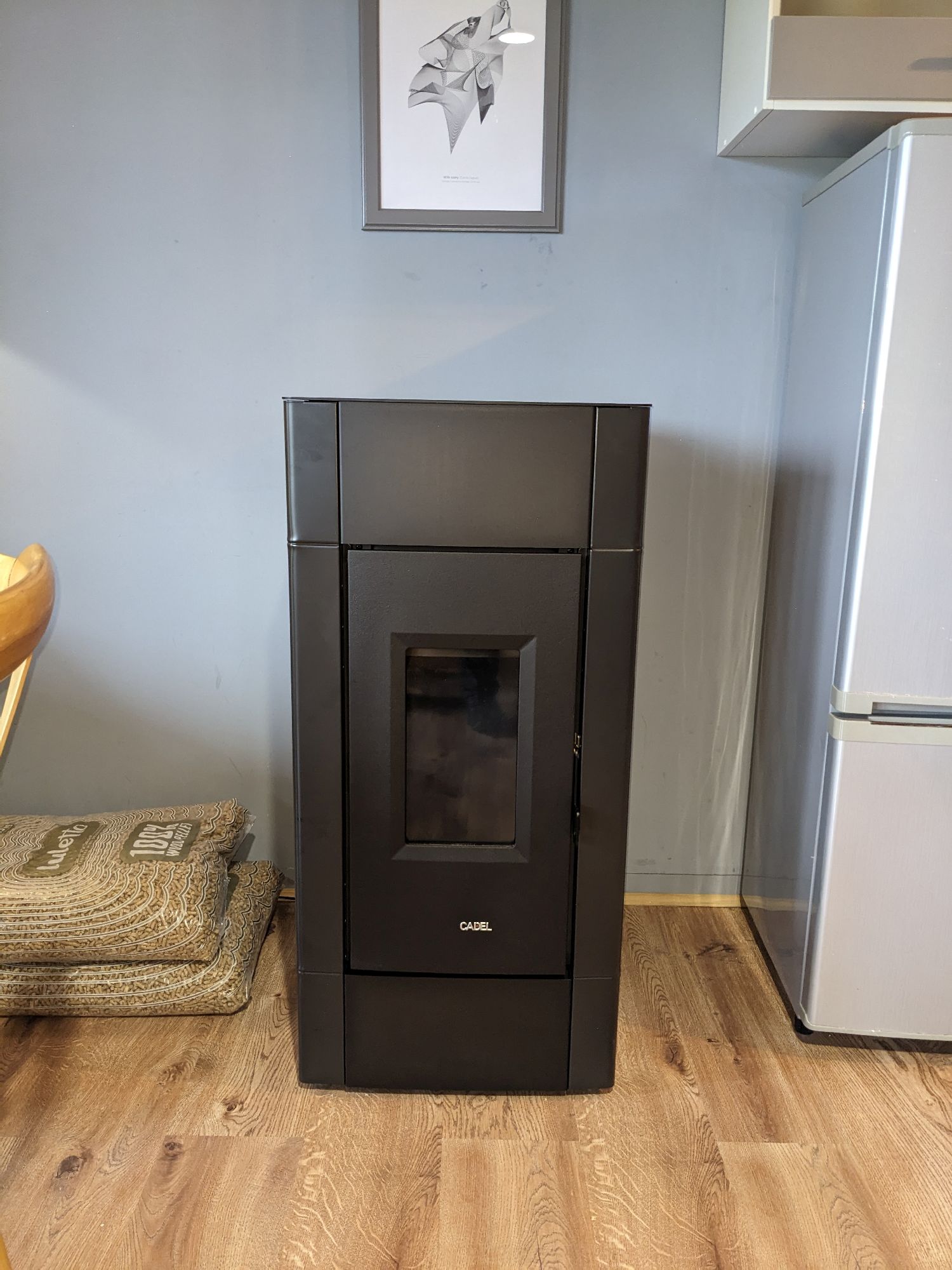 kominek na pellet z marki cadel, obok leżą dwa worki pelletu